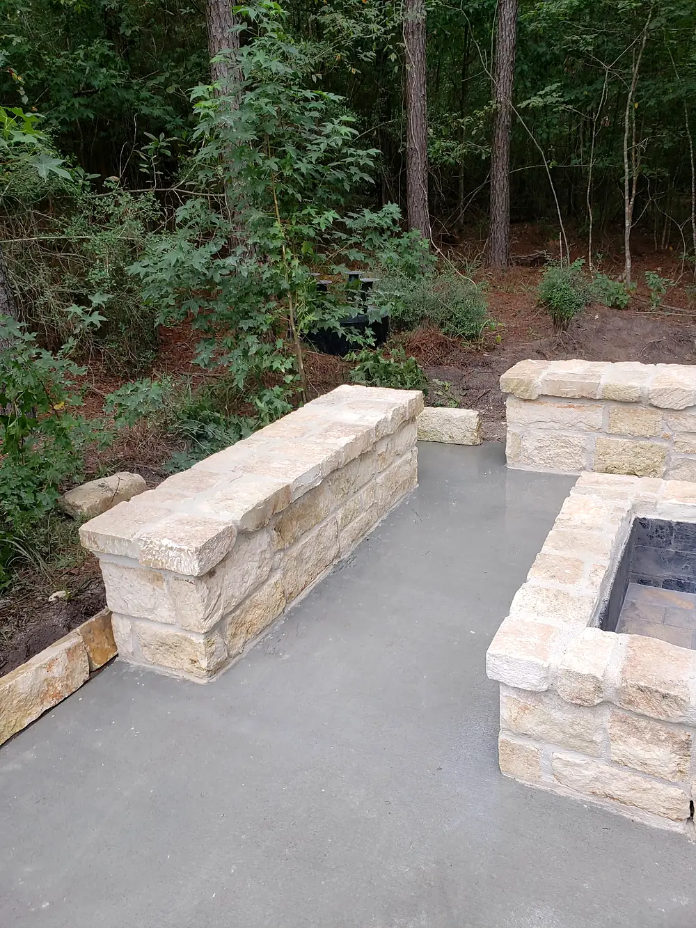 Finished chopped-limestone seat wall and fire pit on a fresh slab