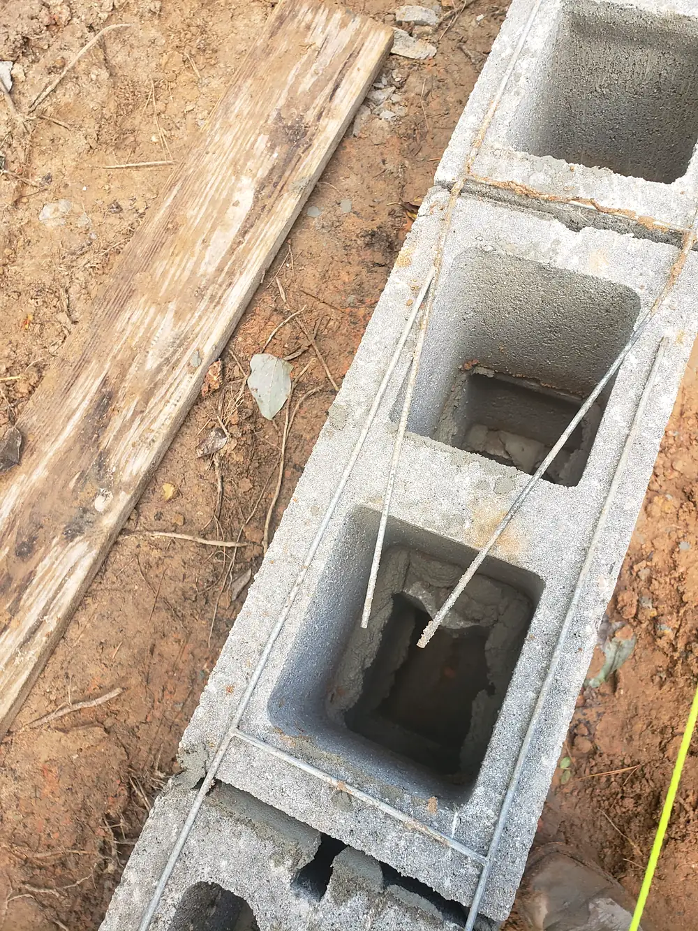 Concrete block wall going up with steel ladder reinforcement and rebar in the cores