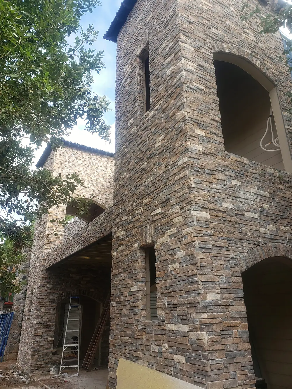 Building with a stone tower and arched balconies, clad in stacked stone